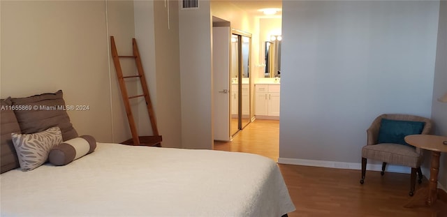 bedroom featuring ensuite bath, a closet, and light hardwood / wood-style floors