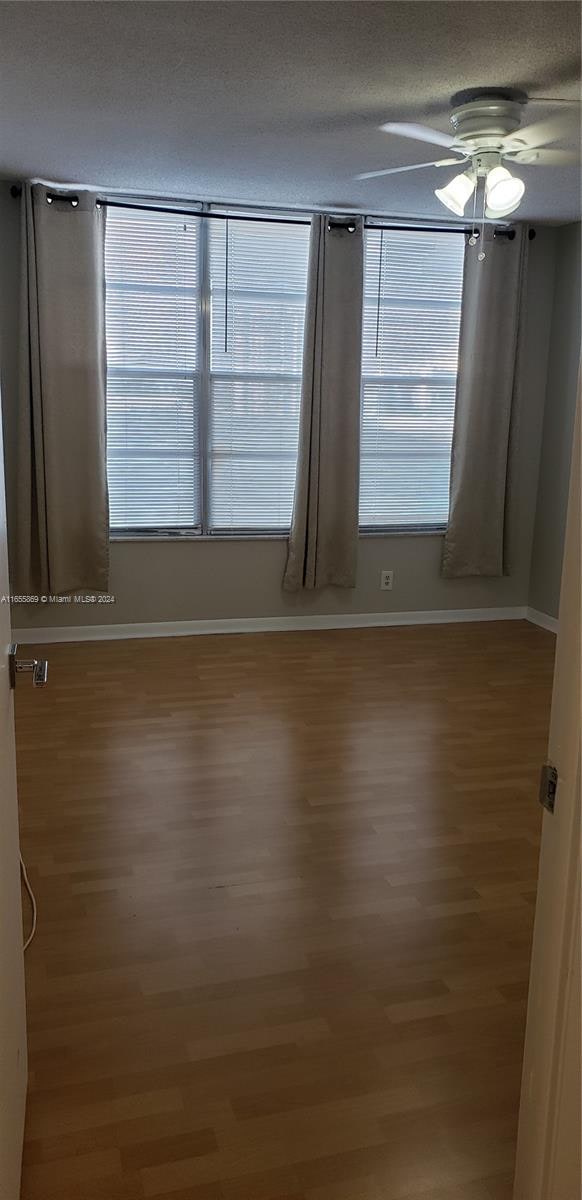 unfurnished room featuring a textured ceiling, hardwood / wood-style flooring, and ceiling fan