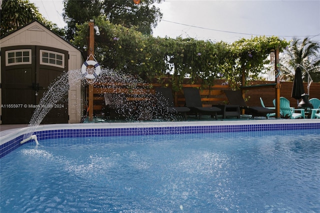 view of pool featuring pool water feature and a shed