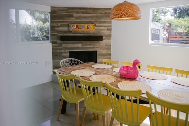 dining area with tile patterned flooring, wood walls, and a fireplace