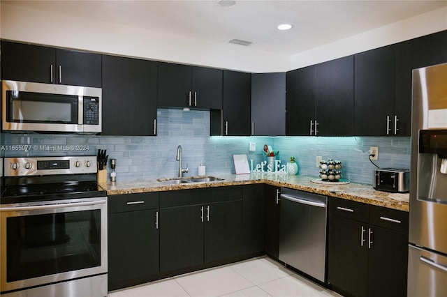 kitchen featuring appliances with stainless steel finishes, light stone counters, backsplash, and sink