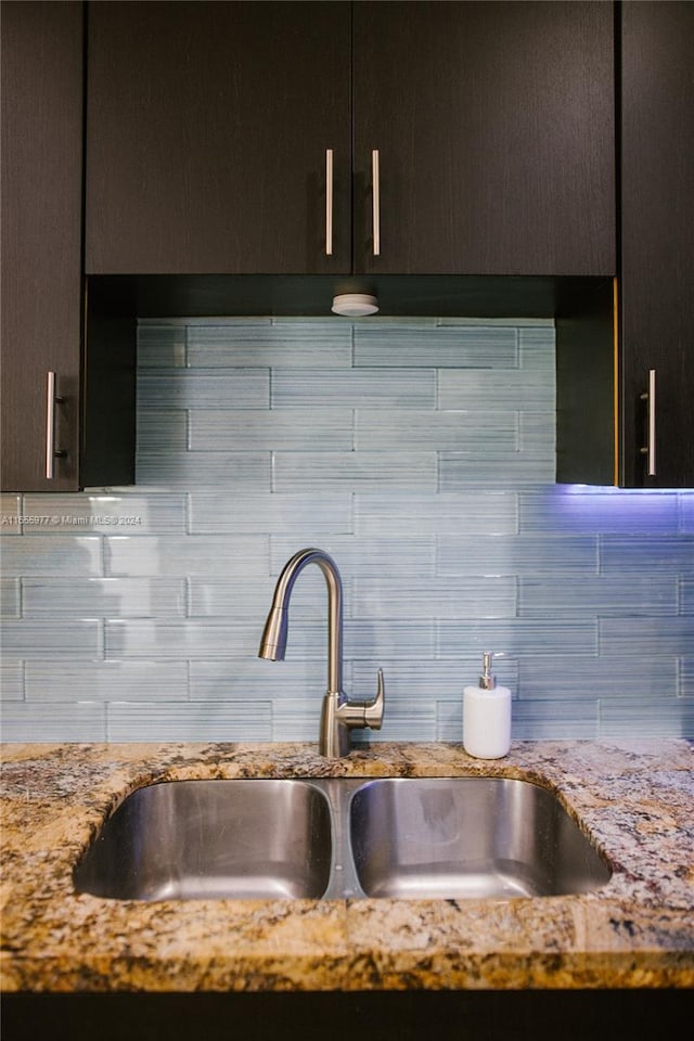 room details with dark brown cabinets, light stone counters, sink, and decorative backsplash