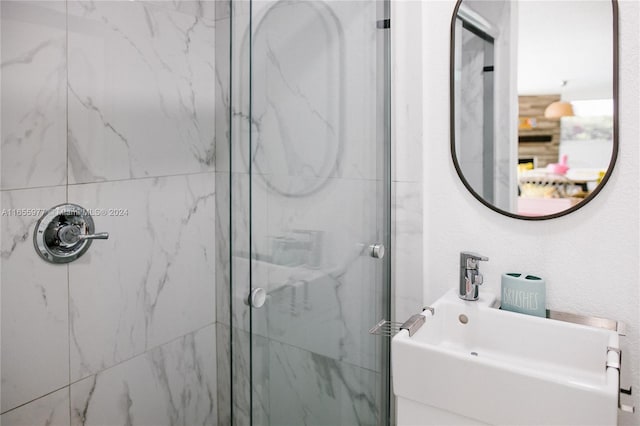 bathroom with a shower with shower door and sink