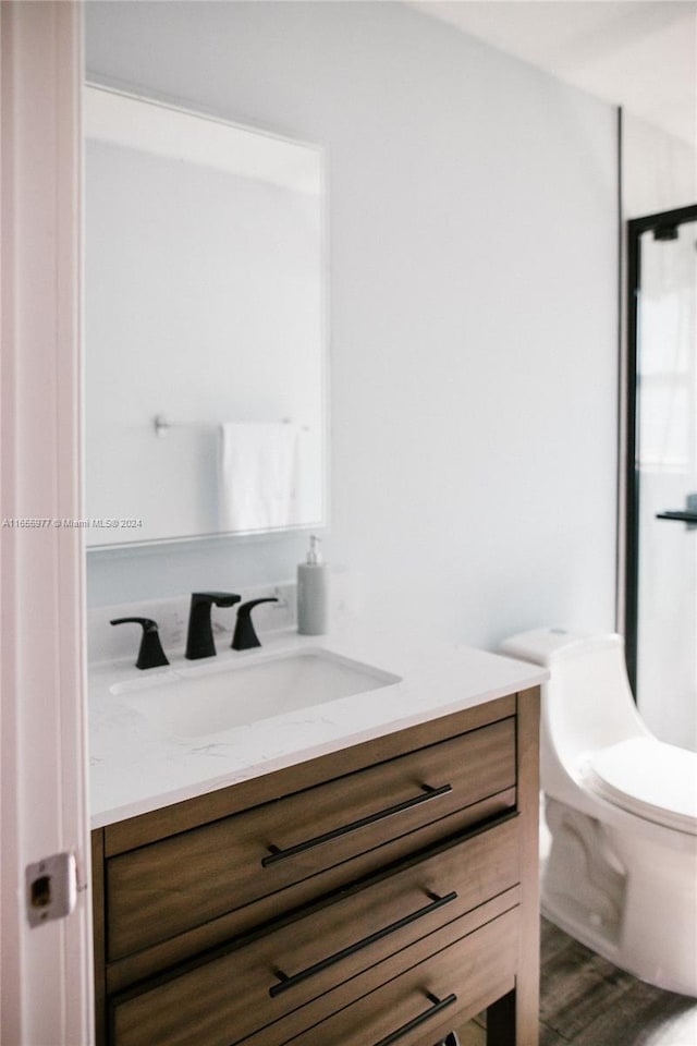 bathroom with vanity, toilet, and hardwood / wood-style floors