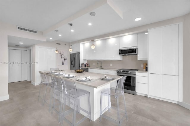 kitchen featuring white cabinets, pendant lighting, sink, stainless steel appliances, and a center island