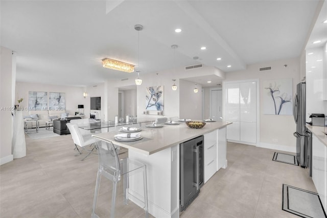 kitchen with wine cooler, white cabinetry, hanging light fixtures, a kitchen island, and stainless steel fridge