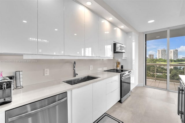 kitchen featuring sink, white cabinetry, decorative backsplash, appliances with stainless steel finishes, and light tile patterned floors