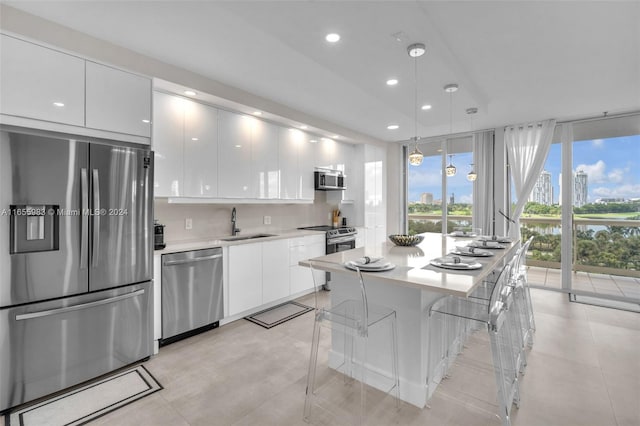 kitchen featuring sink, white cabinetry, hanging light fixtures, backsplash, and appliances with stainless steel finishes