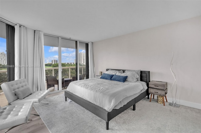 bedroom featuring light hardwood / wood-style floors, expansive windows, and access to exterior