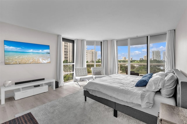 bedroom with expansive windows and light hardwood / wood-style flooring