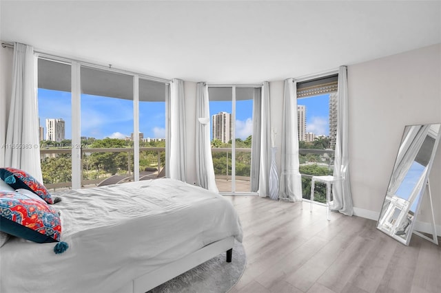 bedroom featuring light hardwood / wood-style flooring, floor to ceiling windows, and access to outside