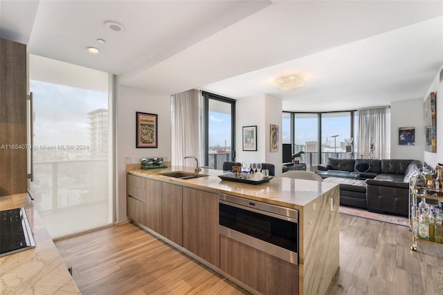 kitchen featuring kitchen peninsula, light hardwood / wood-style flooring, floor to ceiling windows, and sink