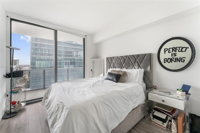 bedroom featuring hardwood / wood-style flooring and a wall of windows