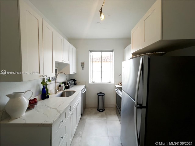 kitchen featuring stainless steel appliances, light stone counters, and white cabinetry