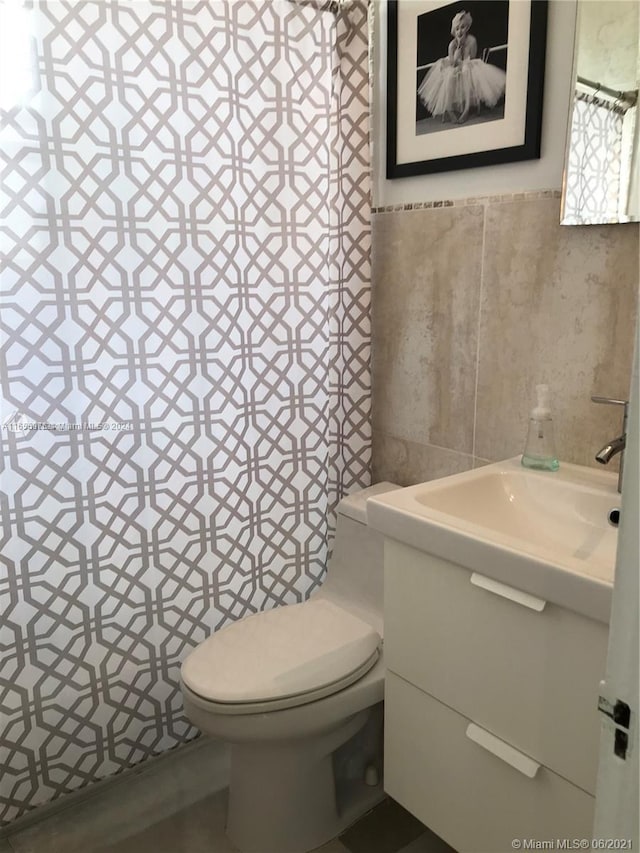 bathroom with vanity, toilet, and tile walls