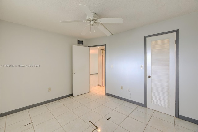 unfurnished bedroom with light tile patterned flooring, a closet, a textured ceiling, and ceiling fan