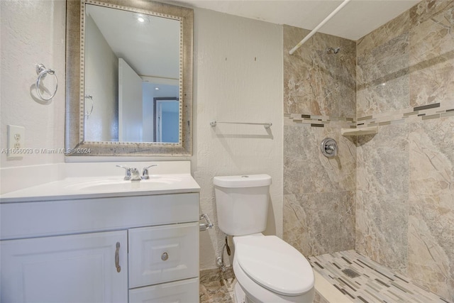 bathroom featuring vanity, a tile shower, and toilet