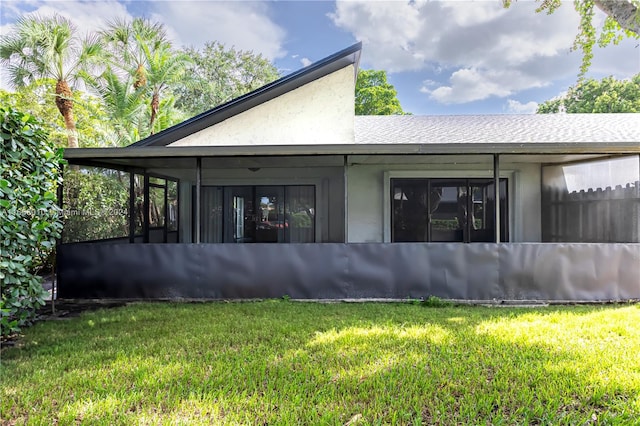 rear view of house featuring a lawn and a sunroom