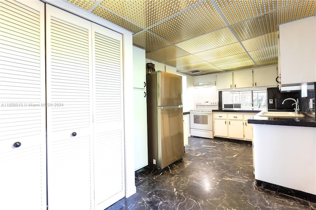 kitchen featuring stainless steel fridge, cream cabinetry, sink, and electric stove