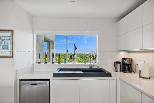 kitchen featuring tasteful backsplash, stainless steel dishwasher, sink, and white cabinets