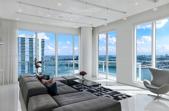 living room with track lighting, a wealth of natural light, a water view, and tile patterned floors