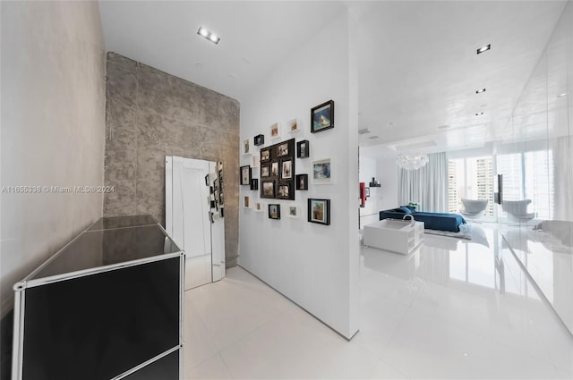 hall with tile walls, a chandelier, and light tile patterned floors