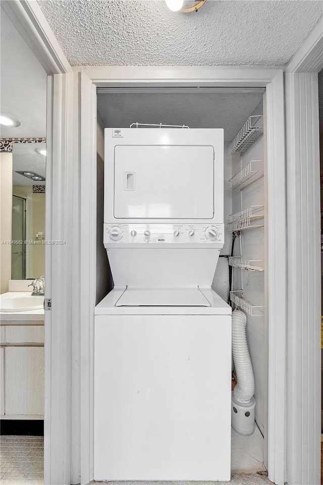 washroom featuring stacked washer and dryer, light tile patterned floors, and sink