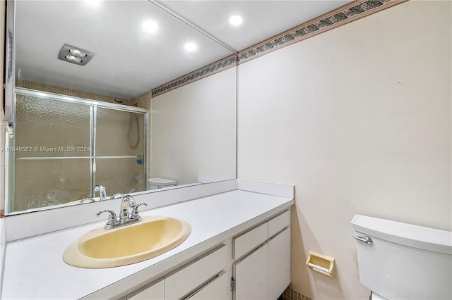 bathroom with an enclosed shower, vanity, and toilet