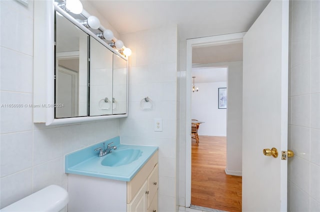 bathroom with hardwood / wood-style floors, toilet, tile walls, and vanity