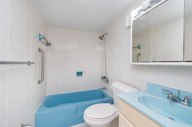 full bathroom featuring tiled shower / bath, vanity, toilet, and tile walls