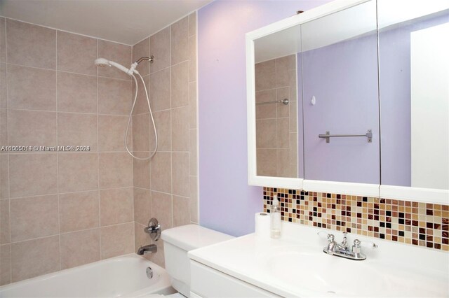 full bathroom with tiled shower / bath, toilet, decorative backsplash, and vanity