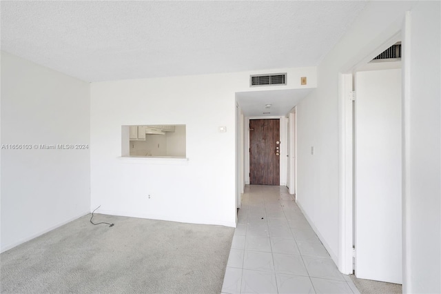 spare room with light carpet and a textured ceiling