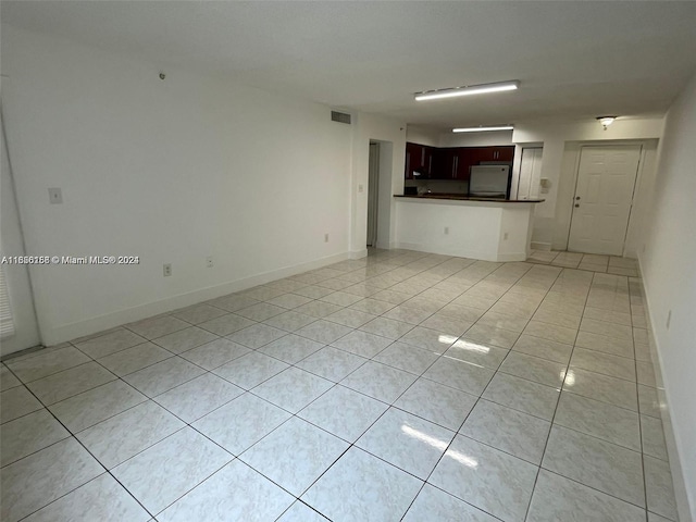 unfurnished living room with light tile patterned floors, visible vents, and baseboards
