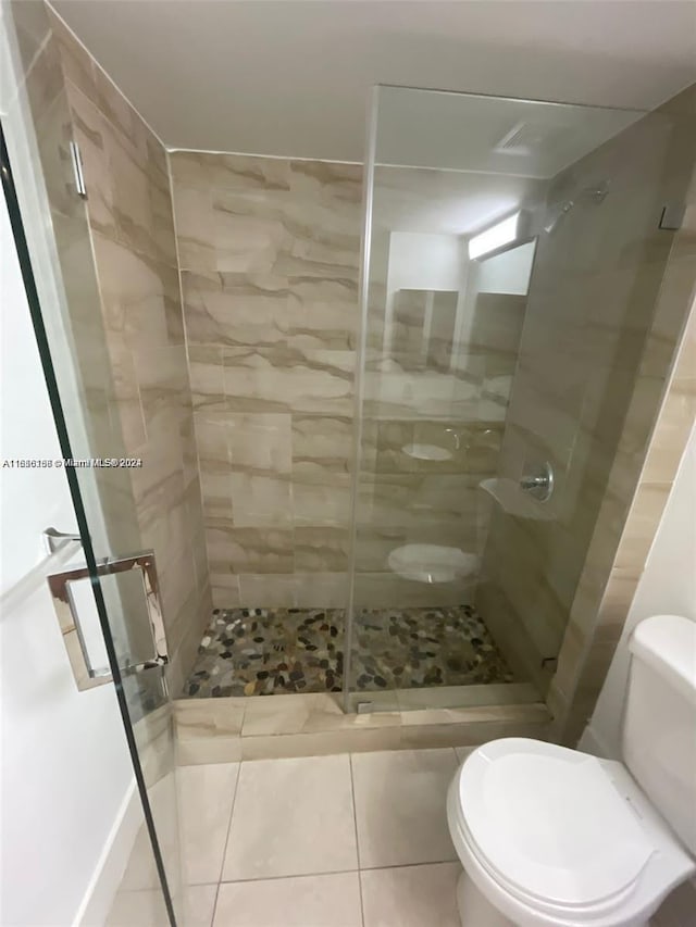 bathroom with tile patterned floors, toilet, and a shower stall
