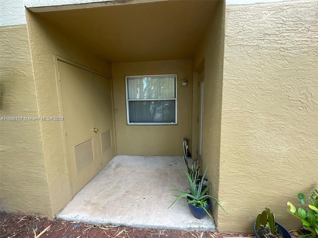 doorway to property featuring visible vents and stucco siding