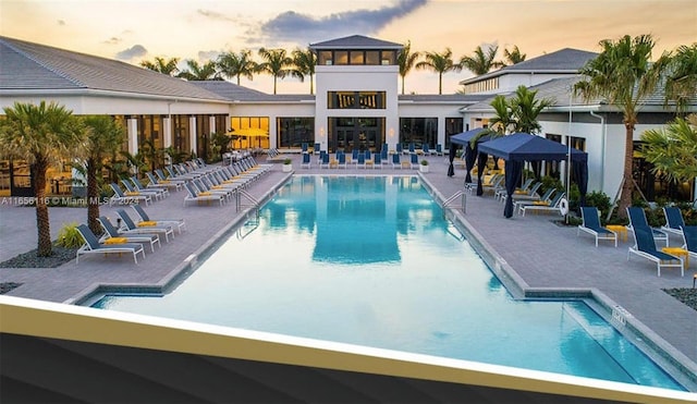 pool at dusk featuring a patio area