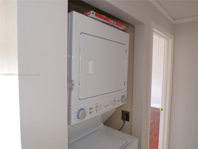 laundry area with hardwood / wood-style flooring and stacked washing maching and dryer