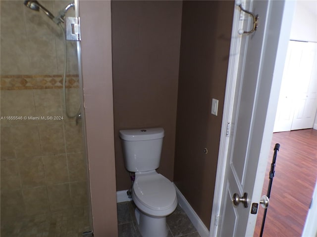 bathroom featuring wood-type flooring, toilet, and a shower with shower door