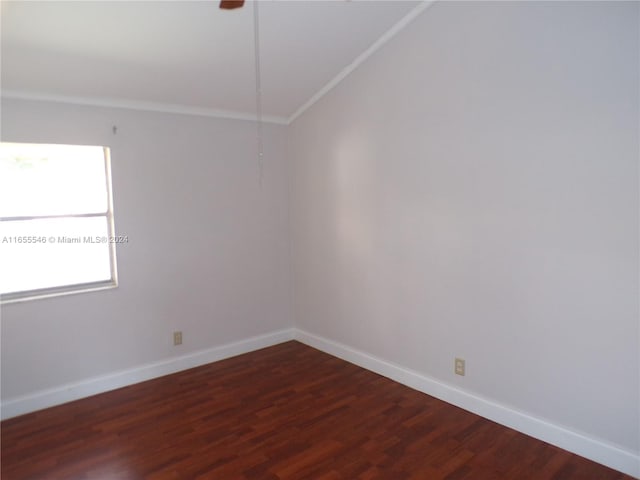 spare room with crown molding, lofted ceiling, and dark wood-type flooring