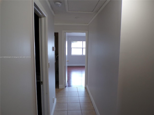 corridor featuring ornamental molding and light tile patterned flooring