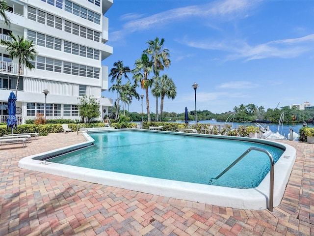 view of swimming pool with a patio and a water view