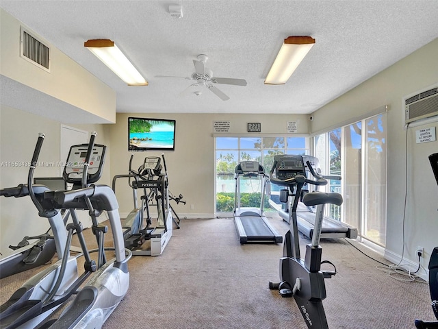 workout area featuring a textured ceiling, light colored carpet, and ceiling fan