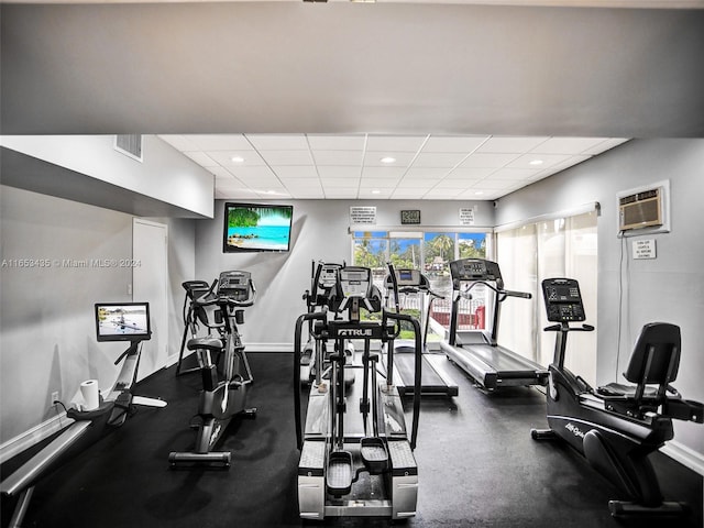 workout area featuring a drop ceiling and an AC wall unit