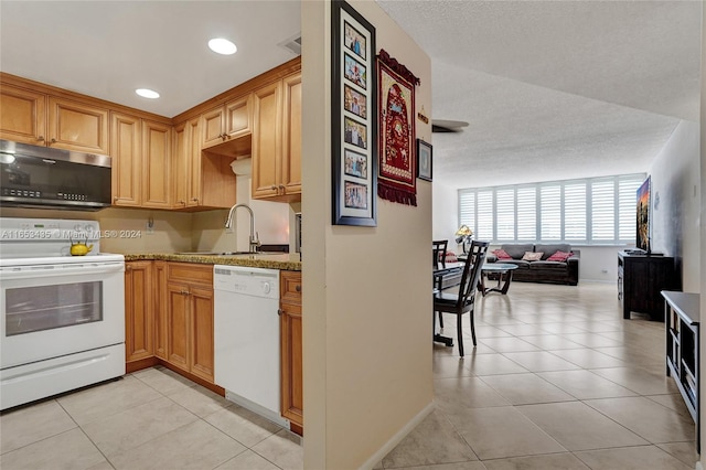 kitchen with sink, light stone countertops, white appliances, and light tile patterned flooring