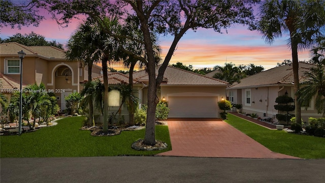 mediterranean / spanish home featuring a lawn and a garage