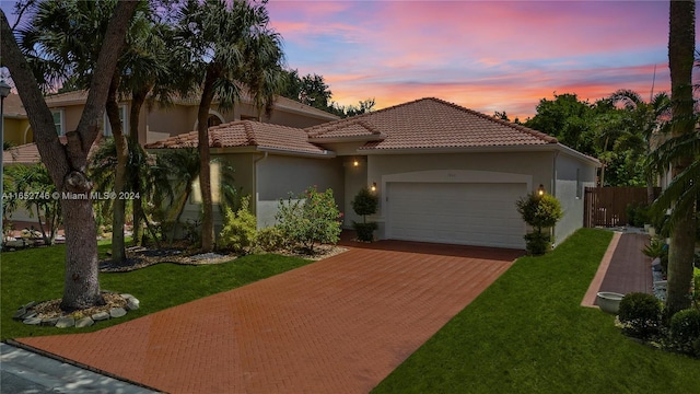 mediterranean / spanish-style house featuring a garage and a yard