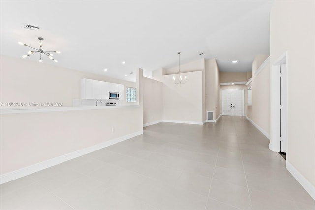 unfurnished room with vaulted ceiling, a chandelier, and light tile patterned floors