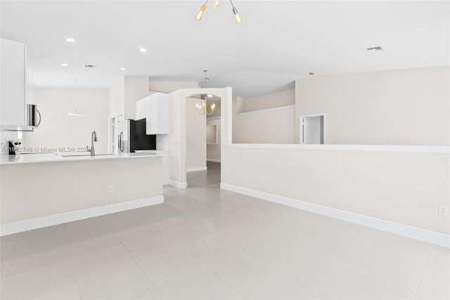 unfurnished living room with sink, light tile patterned floors, and an inviting chandelier