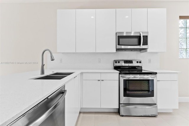 kitchen with white cabinets, appliances with stainless steel finishes, light tile patterned floors, and sink