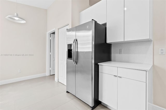 kitchen featuring stainless steel fridge with ice dispenser, light tile patterned flooring, white cabinets, and decorative backsplash